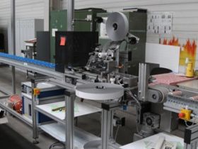 Klebebandaufbringmaschine mit zwei Auftragskoepfen mit einer Vorbehandlungsanlage (Corona) und seitlichen Abtransport der Profile